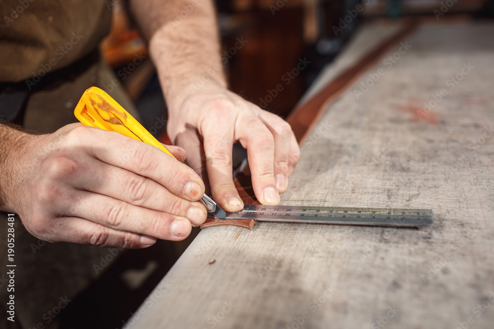 Close up of hands tanner performs work on table with tools Close up of hands tanner performs work on table with tools