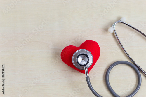 Stethoscope with Strong red heart on wood table on doctor desk with copy space. Check up health for buy insurance concept.