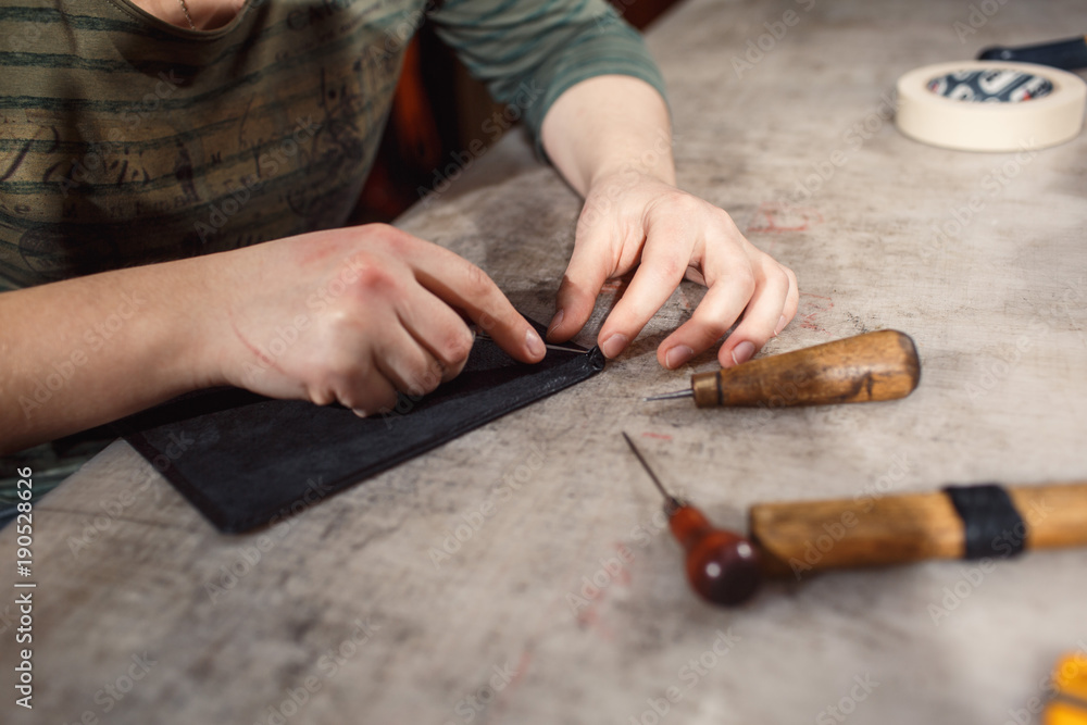 Close up of hands tanner performs work on table with tools Close up of hands tanner performs work on table with tools