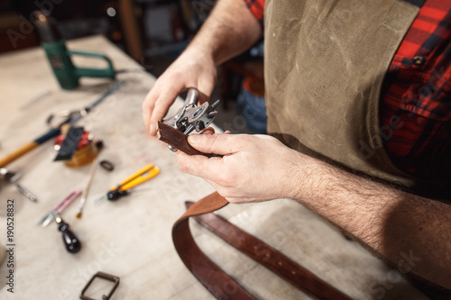 Close up of hands tanner performs work on table with tools