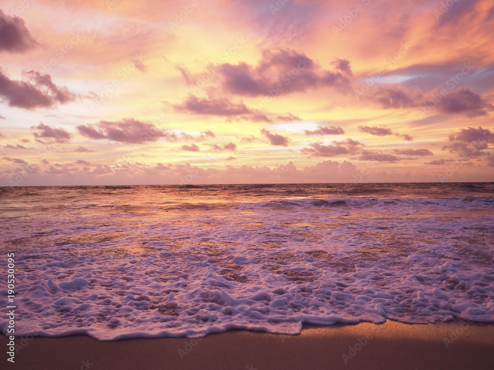 Colorful sunset on the tropical beach with beautiful sky, clouds, soft waves.