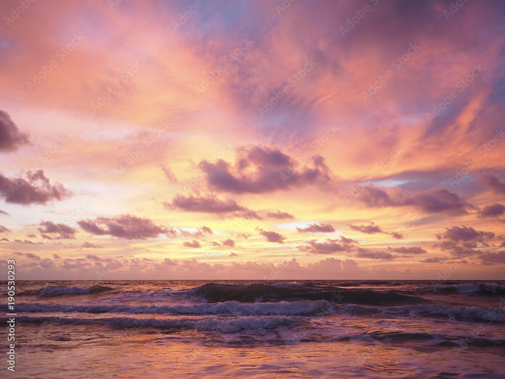 Colorful sunset on the tropical beach with beautiful sky, clouds, soft waves.
