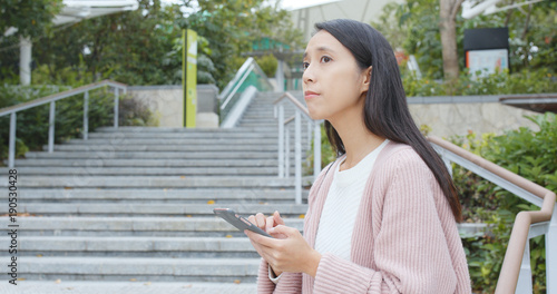 Woman check on cellphone at outdoor, walking down to steps