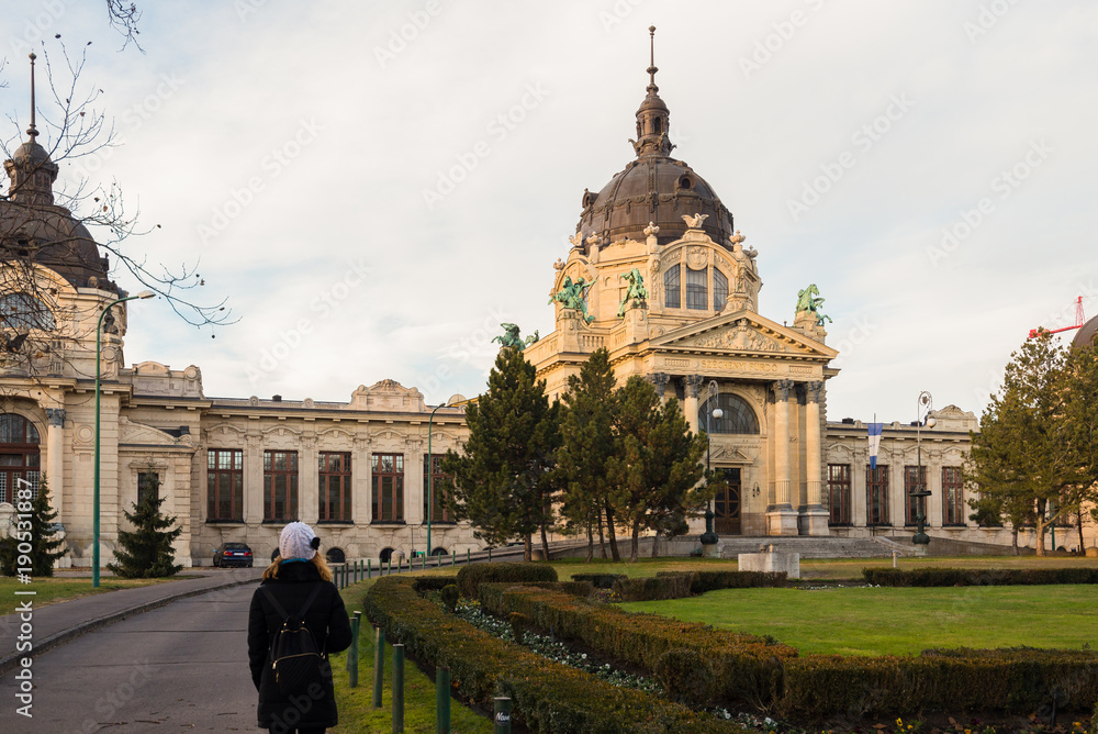 Young woman in front of main entrance to Szechenyi thermal bath in BudaPest, Hungary