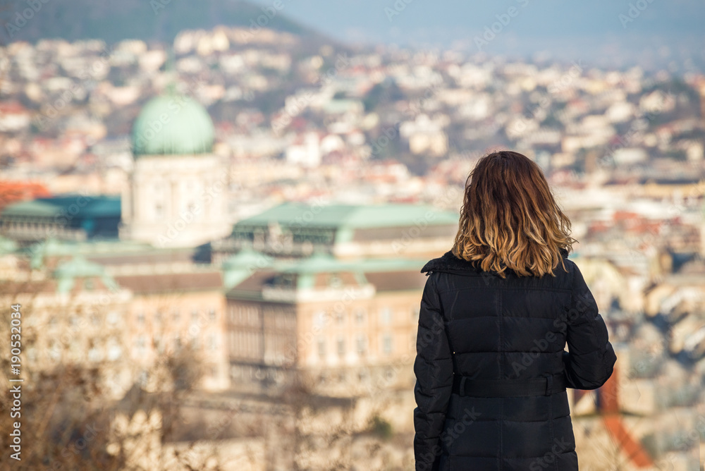 Young woman is looking at the Buda Castle from Citadel on the top of Gellert Hill in Budapest, Hungary.