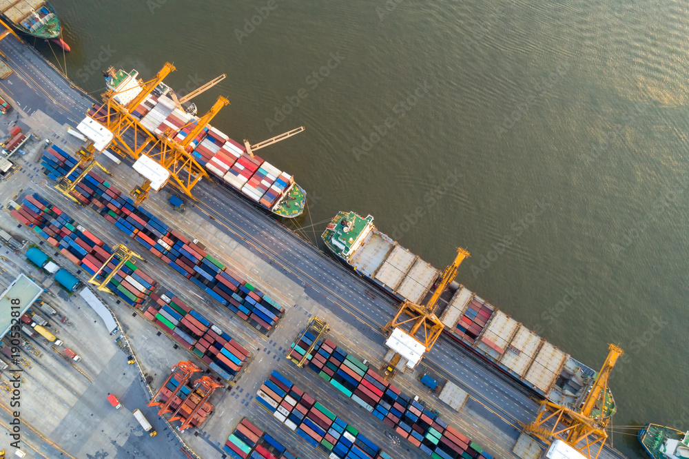 Containers yard in port congestion with ship vessels are loading and discharging operations of the transportation in international port.Shot from drone.