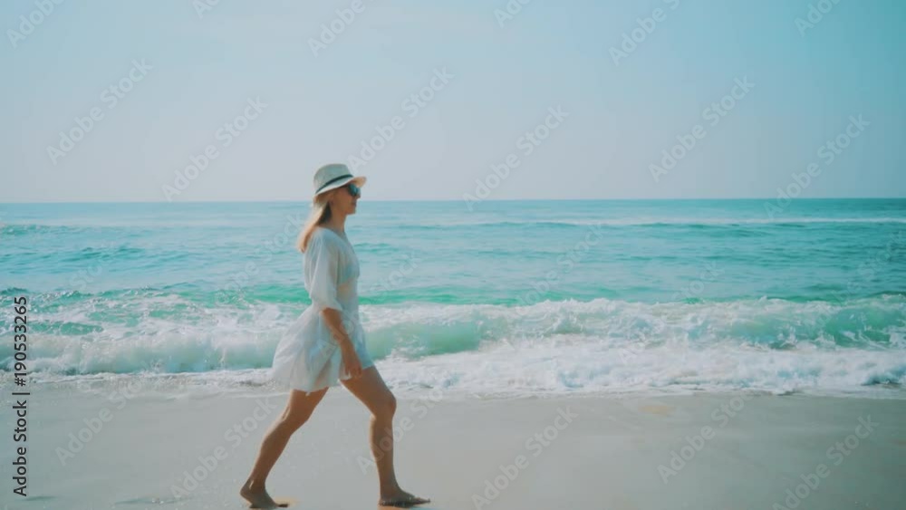 Woman walking on the ocean beach under blue sky in sunny day. Seascape view with palms. Woman walking on the ocean beach under blue sky in sunny day. Seascape view with palms.