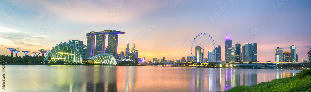 Fototapeta premium Biznesowa dzielnica Singapuru Skyline. W marinie bay piasek i ogród przy zatoce o zachodzie słońca z nowoczesnym wieżowcem z oświetleniem i kolorową chmurą nieba.