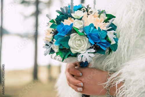 Beautiful bride holding a wedding bouquet of apricot and blue roses