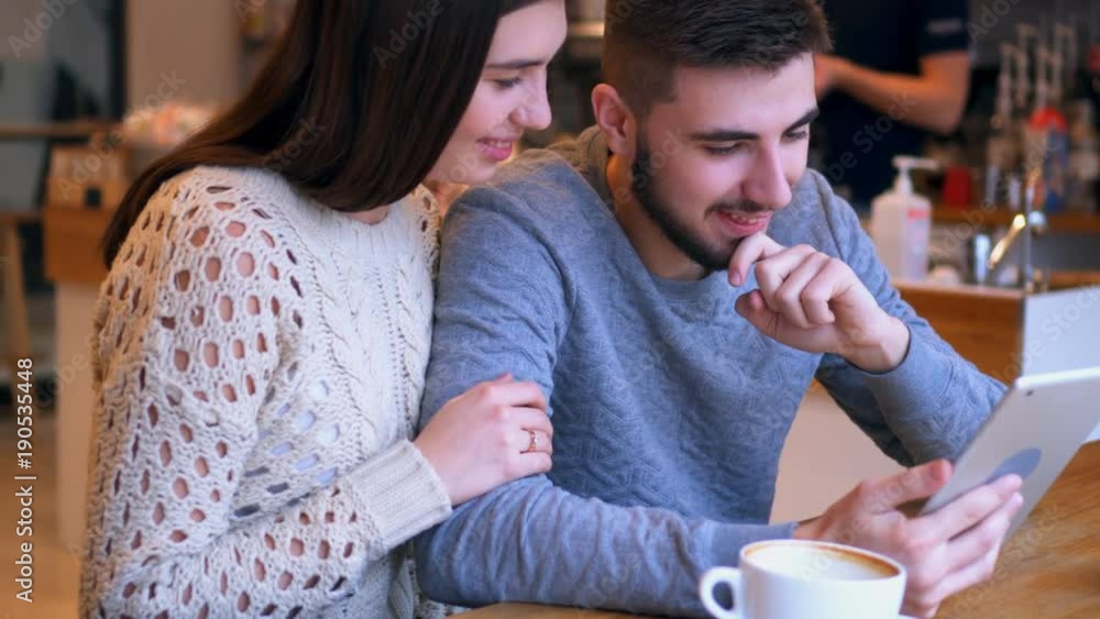 Young couple in love sitting at cafe and using tablet Young couple in love sitting at cafe and using tablet