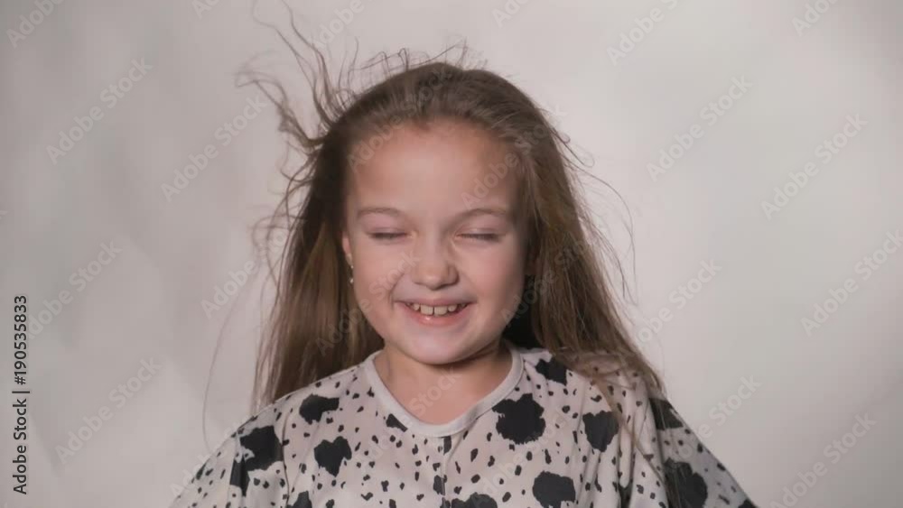 Happy little girl in the studio on a gray background. She jumps, shows different emotions. Hair fluttering from the wind. Super slow motion, shot at 180fps. Happy little girl in the studio on a gray background. She jumps, shows different emotions. Hair fluttering from the wind. Super slow motion, shot at 180fps.