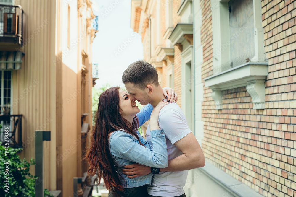 Φωτογραφία The charming young couple in love is smiling and tenderly hugging in the narrow street of Budapest, Hungary