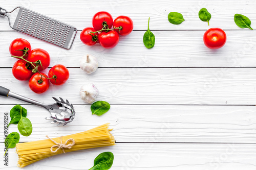 Cook spaghetti with tomatoes, garlic, basil. Italian recipe. White wooden background top view copy space