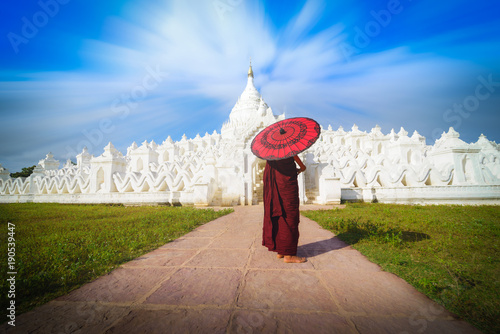 Canvas Print Asian young monk holding red umbrellas on blue sky in the Mya Thein Tan Pagoda at Mingun, Mandalay Myanmar