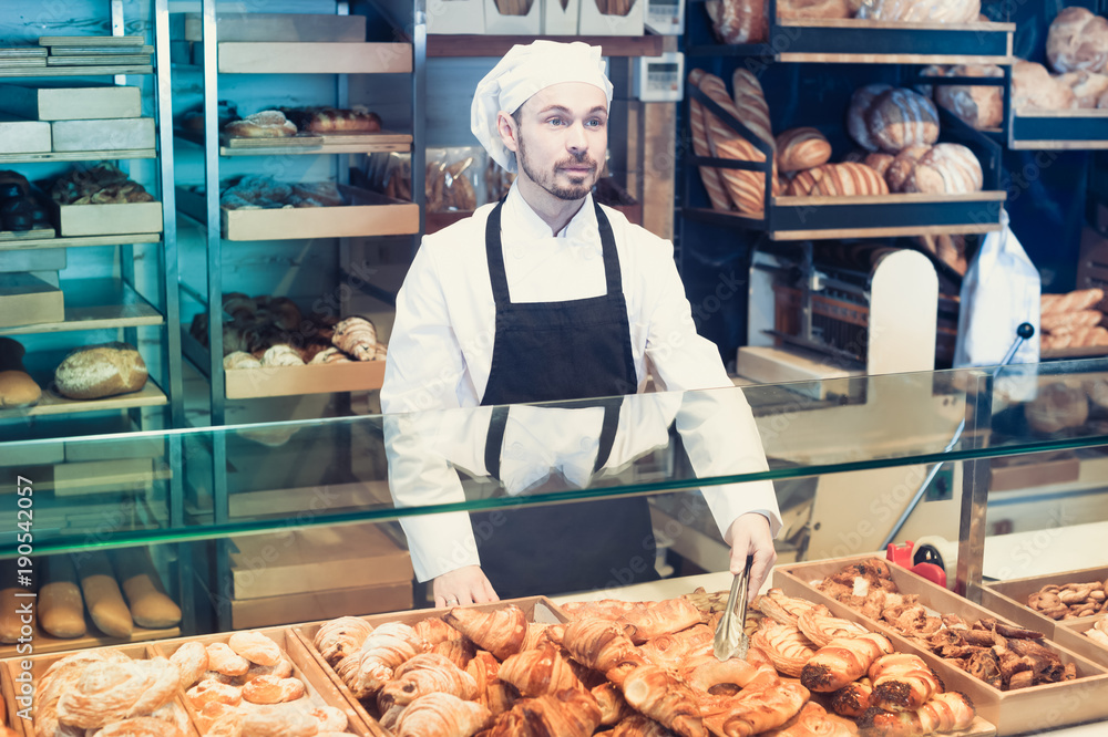 Young male pastry maker demonstrating croissant