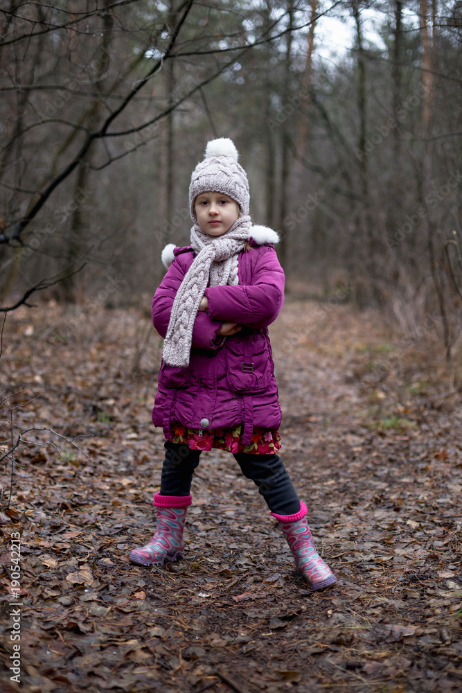 A little girl is standing in a forest on a path. A little girl is standing in a forest on a path.