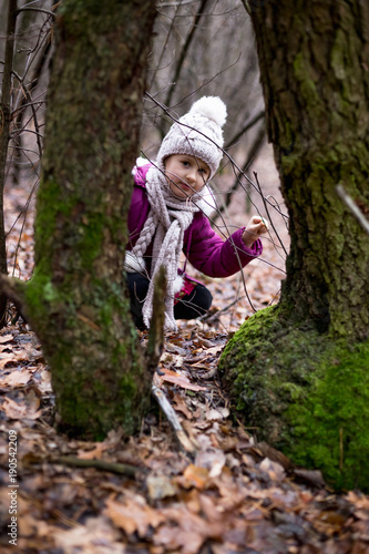 Little cute girl posing near a tree in an autumn forest.