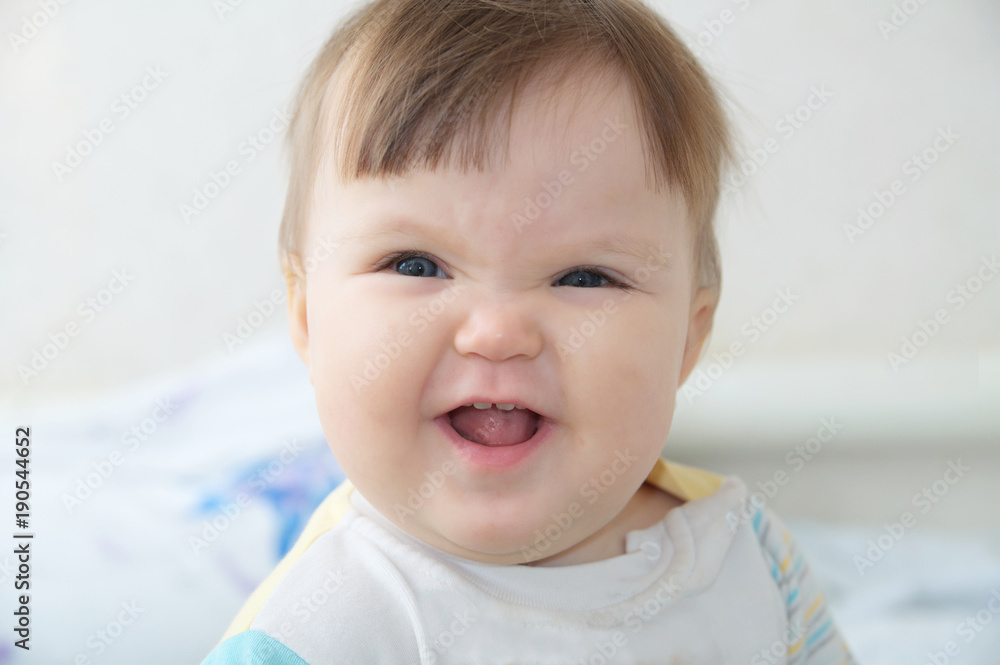 Wrinkling funny infant baby portrait, happy smiling child face expressing emotion, little girl looking at camera making hedgehog grimace, healthy baby care concept Wrinkling funny infant baby portrait, happy smiling child face expressing emotion, little girl looking at camera making hedgehog grimace, healthy baby care concept
