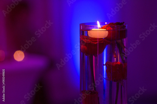 Glass vase with red roses water and light candles 