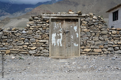 Old wooden gate in a stone wall in the Himalayan mountains. Old Kagbeni. Upper Mustang. Nepal.