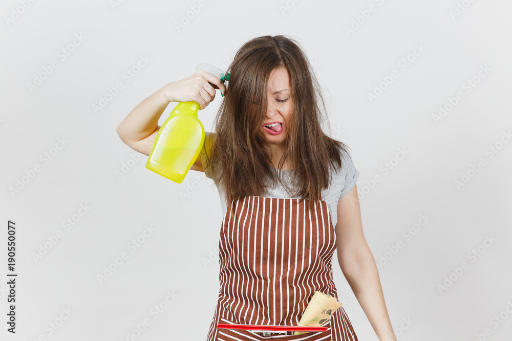 Obraz premium Young fun crazy loony wild screaming housewife tousled hair in apron squeegee rag in pocket isolated on white background. Mad woman shoot from spray bottle with cleaner liquid, pink gloves. Copy space