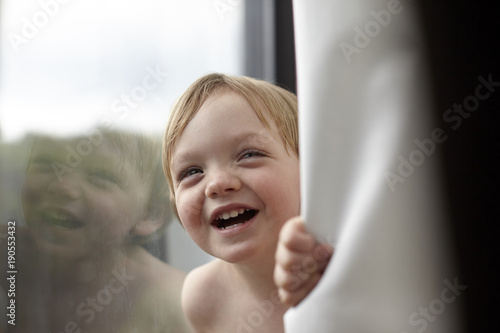 Portrait of smiling toddler boy by window photo
