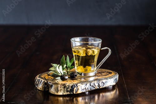 Greek mountain tea in a glass cup and olive leaves on a wooden table.  photo