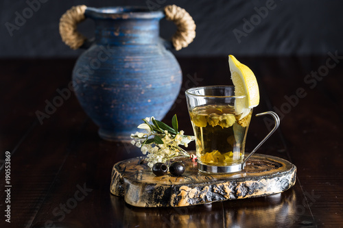 Greek mountain tea with lemon in a glass cup and olive leaves with a blue Greek pot background. photo