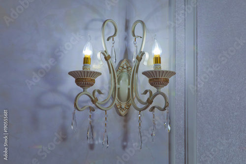 Elegant wall lamp . Stylish lamp on the wallpaper . Wall light of gilded metal with two electric candles . vintage wall lamp isolated on white with clipping path