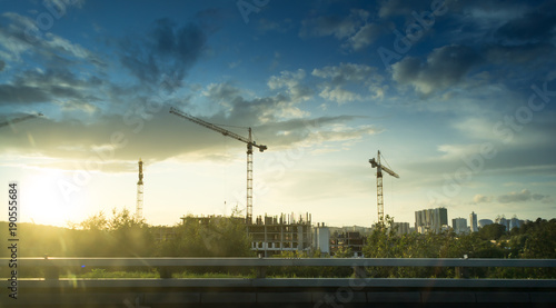 Industrial construction cranes at construction site building up high rise building in big city downtown