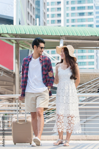 Couple lover travelling in city with baggage during valentine season, young man and woman wearing casual cloth with hat and sun glasses going honeymoon travel after the married in city town.