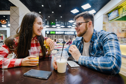 couple make pause for shopping eat burgers in mall cafe