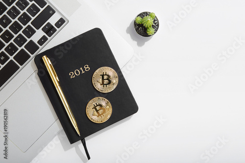 Cryptocurrency coins Bitcoin on computer laptop keyboard, 2018 planner notebook office flat lay
