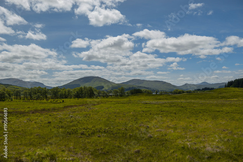 Mountain landscape in the Glencoe area in Scotland, Springtime view mountains with grassland and countryside road in the valley of the Scottish highland near Glencoe