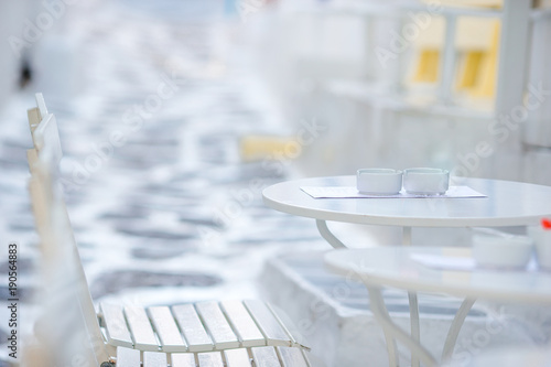 Fototapeta Naklejka Na Ścianę i Meble -  Outdoor cafe on a street of typical greek traditional village in Greece. Coffee on table for breakfast