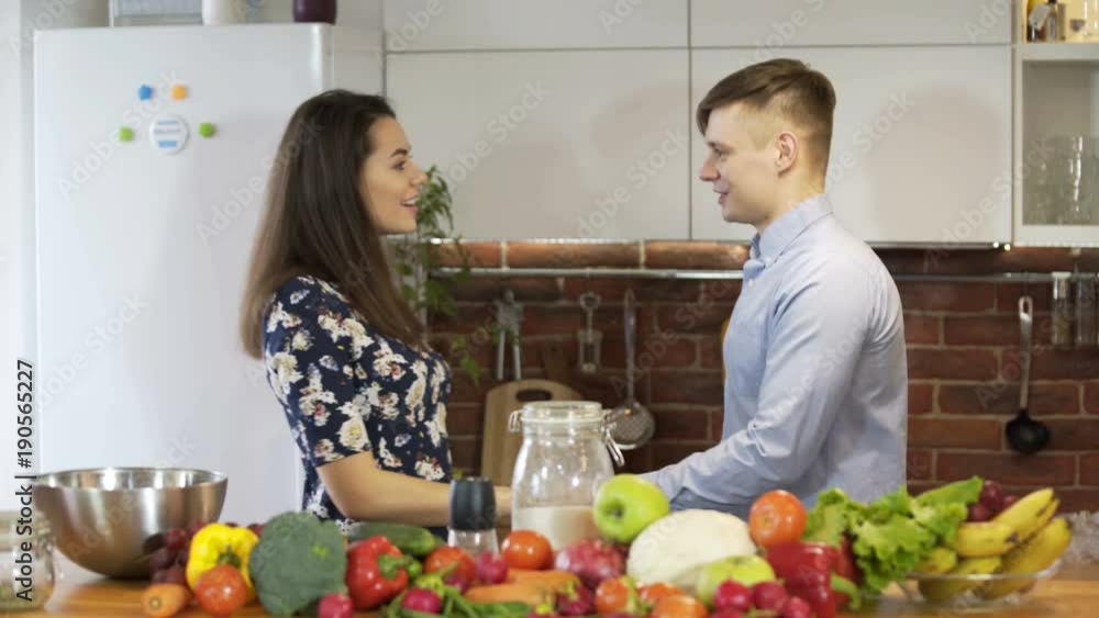 Attractive young couple cooking and chatting in Kitchen Attractive young couple cooking and chatting in Kitchen