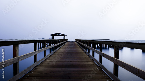 A beautiful pier in the middle of a foggy lake 