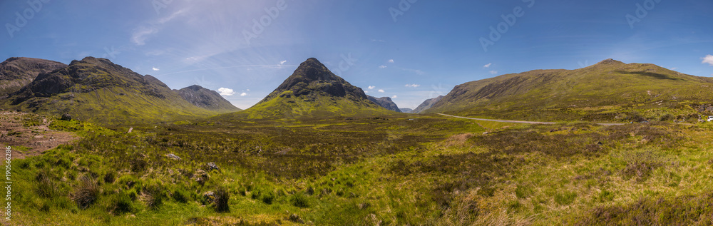 Mountain landscape in the Glencoe area in Scotland, Springtime view mountains with grassland and countryside road in the valley of the Scottish highland near Glencoe