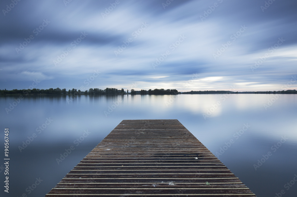 Fototapeta premium The jetty at the Valkenburg lake on a cloudy evening.