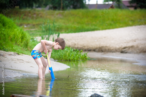 Fototapeta Naklejka Na Ścianę i Meble -  Portrait of caucasian little boy in straw hat playing toys and water pump on the beach.