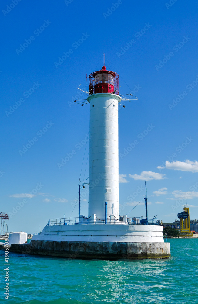 Odessa red and white lighthouse in bright sunny summer day in the middle of the Black Sea. Blue sky and calm water, horizontal orientation