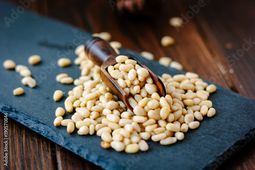 Pine nuts on a black slate with wooden scoop photo