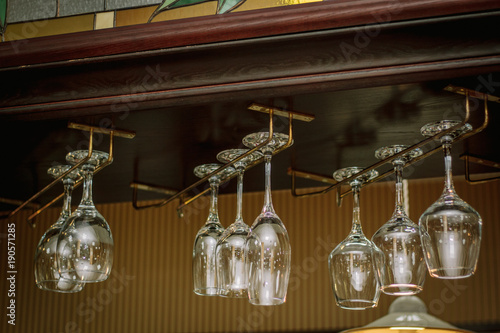 Wine glasses in a bar on wooden rack.