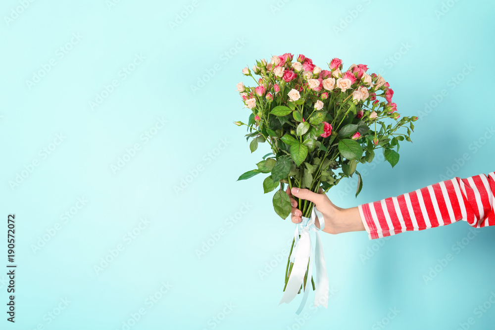 Fototapeta premium Woman with beautiful bouquet of roses on color background