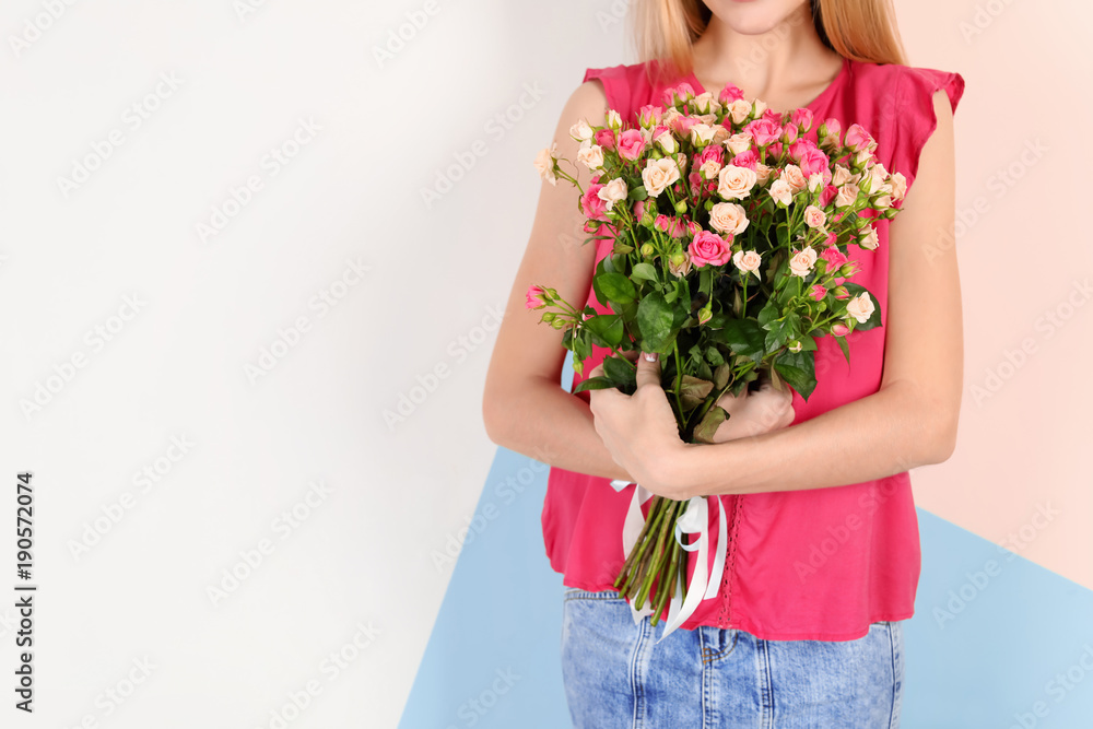 Young woman with bouquet of roses on color background