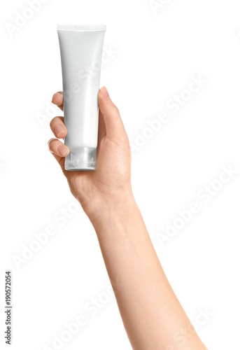 Young woman holding tube of hand cream on white background