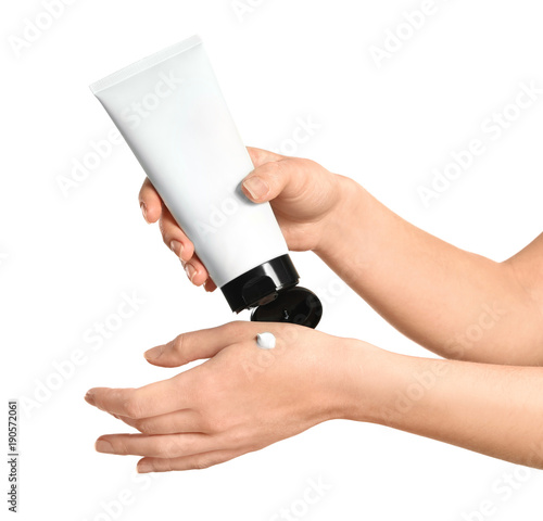 Young woman applying hand cream, on white background