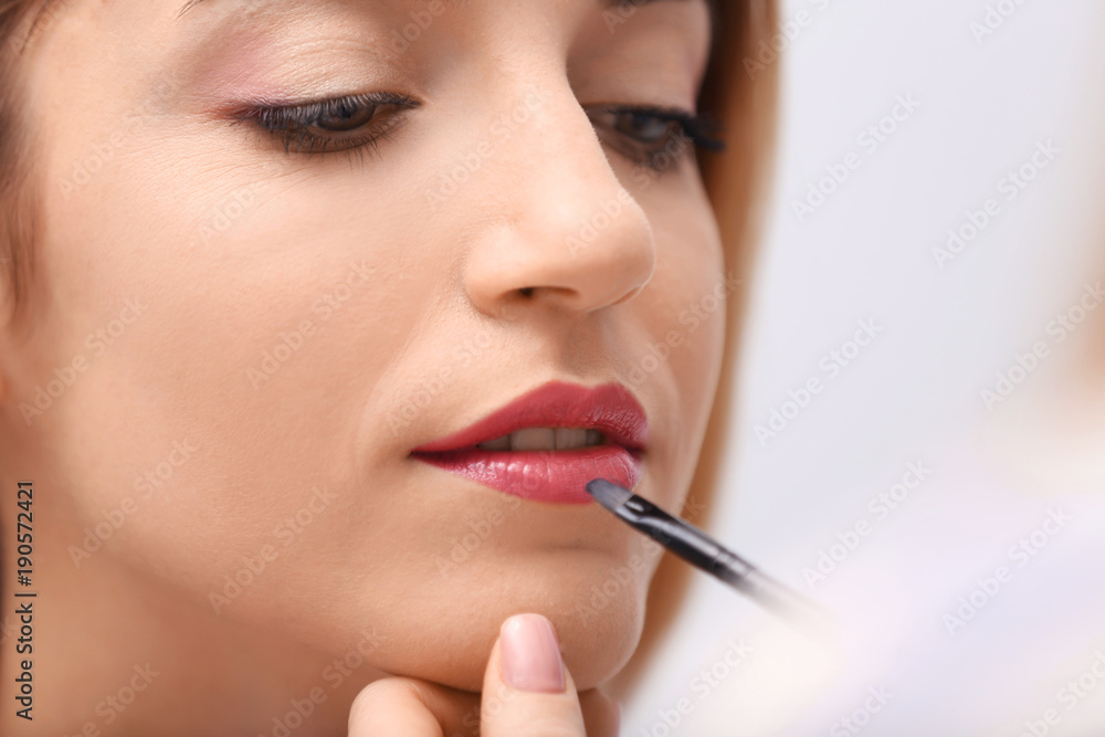 Makeup artist working with beautiful model, closeup
