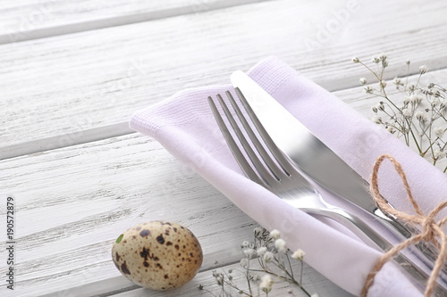 Beautifully decorated cutlery for Easter table setting on wooden background