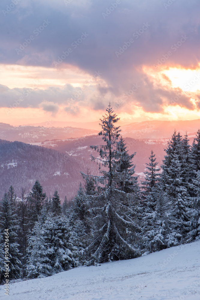 Naklejka premium Malowniczy zachód słońca zimą w górach z widokiem na las